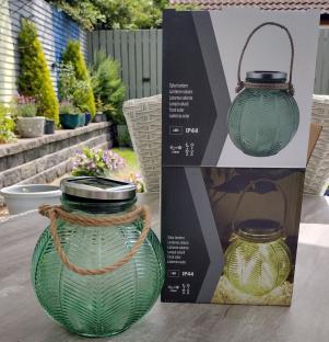 Green solar-powered glass lantern with a rope handle.