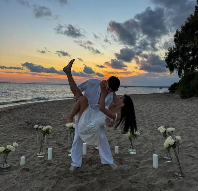 Emily Miller and Cam Holmes announcing their engagement on a beach at sunset.