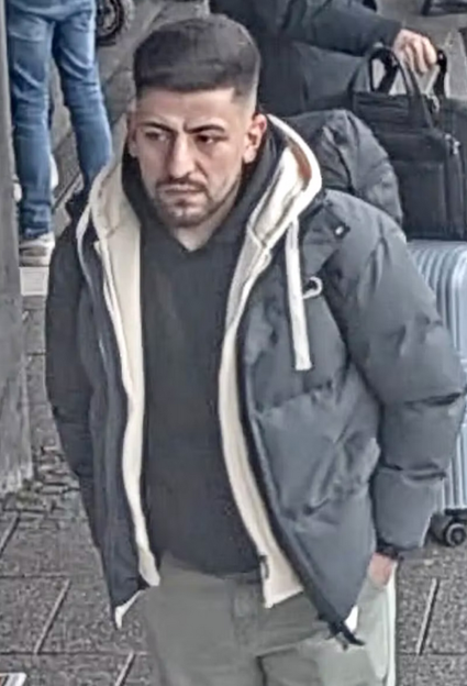 A man in a dark puffer jacket over a light-colored hoodie.