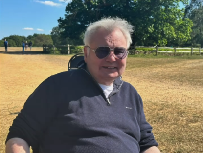 Man in sunglasses sitting outdoors.