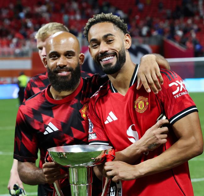 Manchester United players celebrating with a trophy.