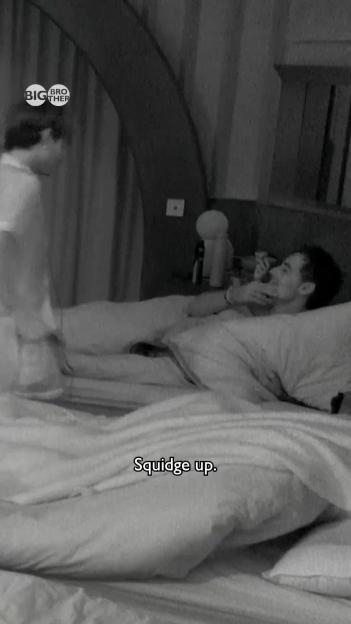 A black and white image of a man in bed, covering his mouth as another person in a robe stands over him, with "Squidge up" text on the blanket.