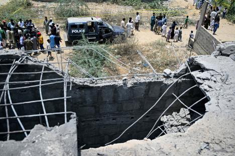 Aftermath of a drone strike in Karachi, Pakistan; police and onlookers at the scene.