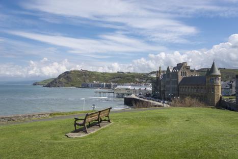 View from a castle of a promenade, university building, and pier in a seaside town.
