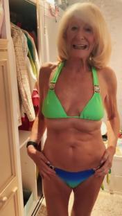 A woman in a green and blue bikini stands in front of a closet.