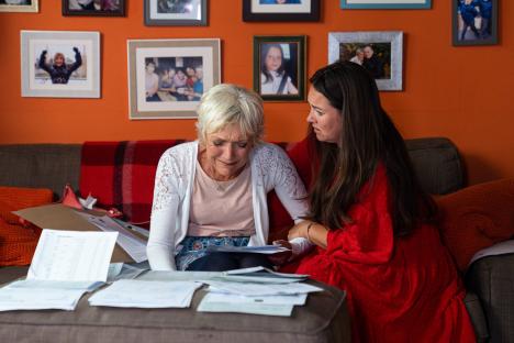 Two women reviewing financial documents, one appearing distressed.