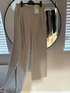 Beige trousers hanging on a clothes hanger.