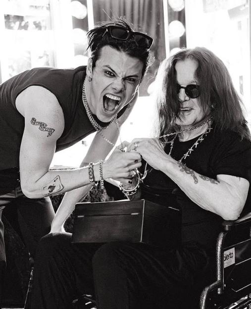 Black and white photo of Ozzy Osbourne receiving a gift from a younger man.