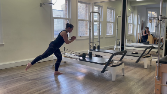 Woman doing a leg exercise on a Pilates reformer.