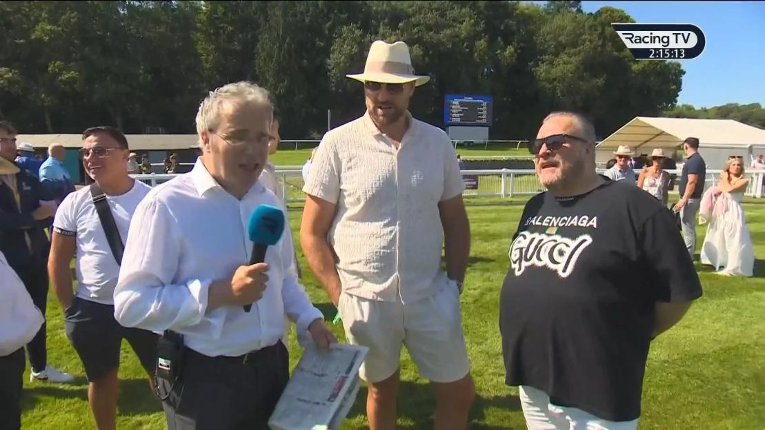 Reporter interviewing two men at a race track.