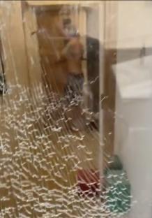 Security camera footage of a man smashing a door and window with an axe.