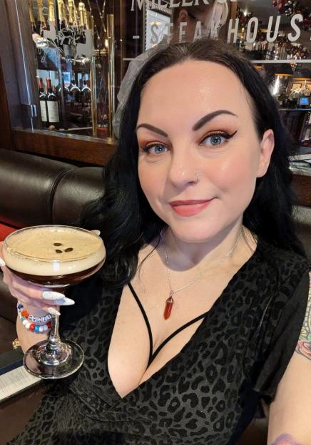 Woman holding espresso martini in a steakhouse.
