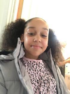 Photo of a girl wearing a gray jacket and a pink shirt with a leopard print.