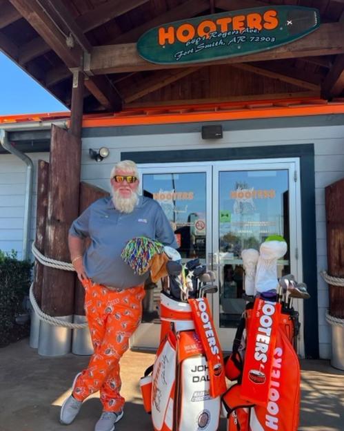 John Daly at a Hooters restaurant with golf clubs.