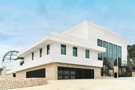 Modern white building with large windows and a stone facade.