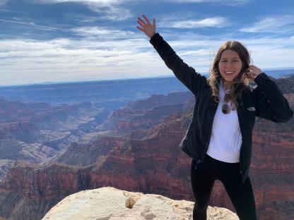 Woman at the Grand Canyon with arm raised.