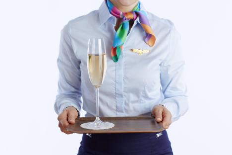 Flight attendant holding a tray with a glass of champagne.