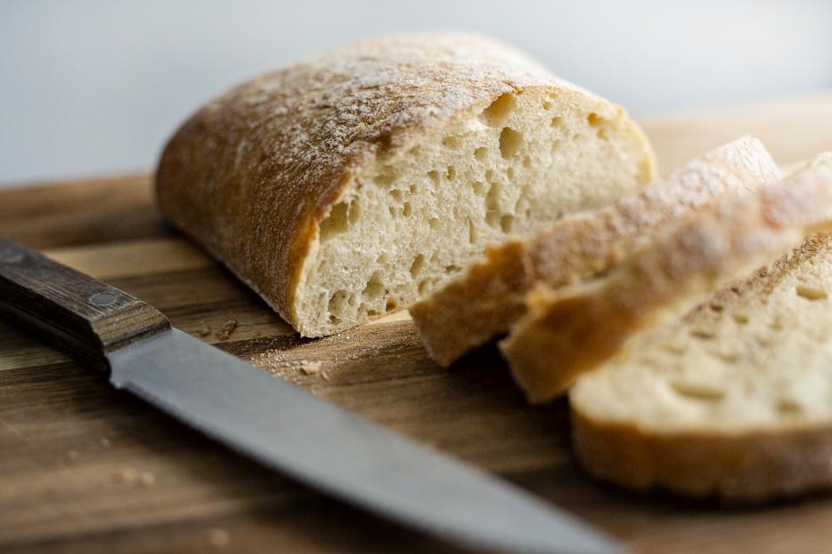 Sliced white bread on a wooden cutting board with a knife.