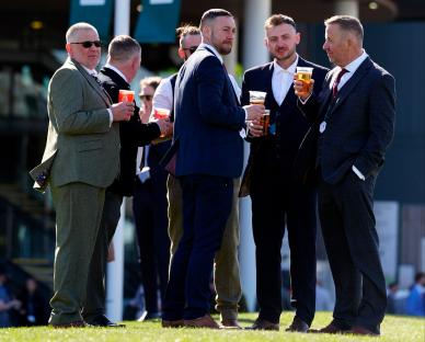 Men in suits socializing at the Randox Grand National Festival.