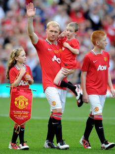 Paul Scholes of Manchester United waves to fans with his children before a testimonial match.
