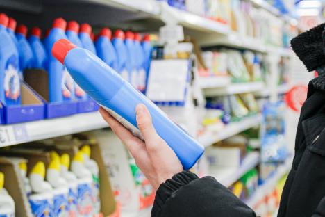 Person examining a blue cleaning product bottle in a store.