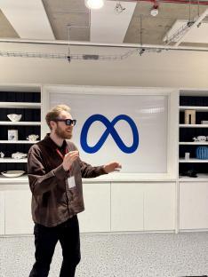 Man gesturing in front of a Meta logo.