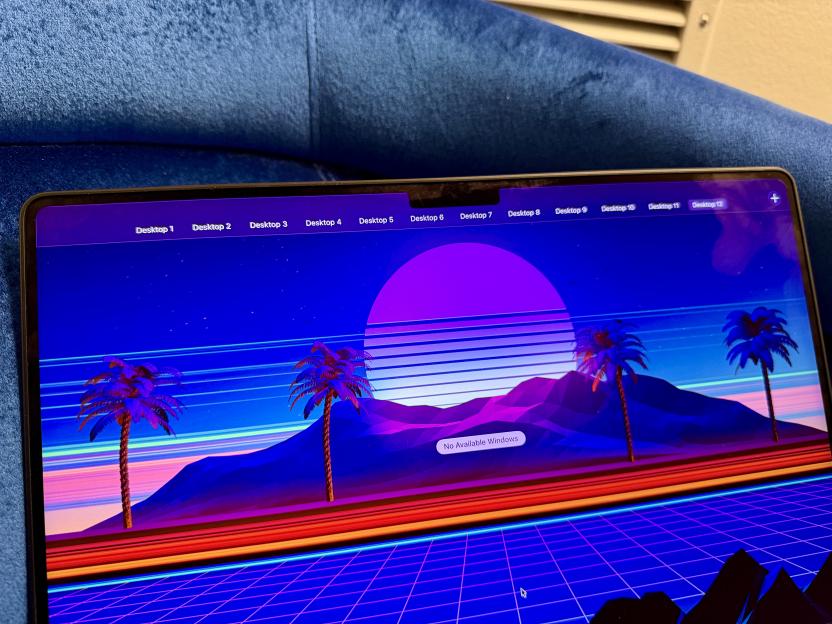 A MacBook Pro screen displaying 12 desktops and a retro-futuristic wallpaper with palm trees, mountains, a large sun, and a grid.