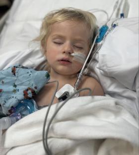 Toddler on life support in a hospital bed.