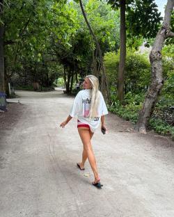 Woman walking down a path in a white shirt and red bikini bottoms.