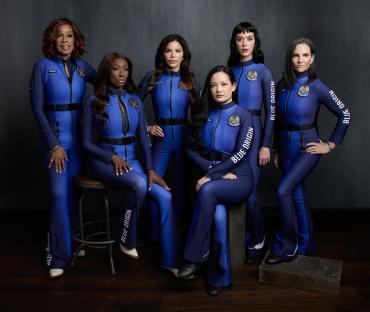 Six women in blue spacesuits pose for a photo.