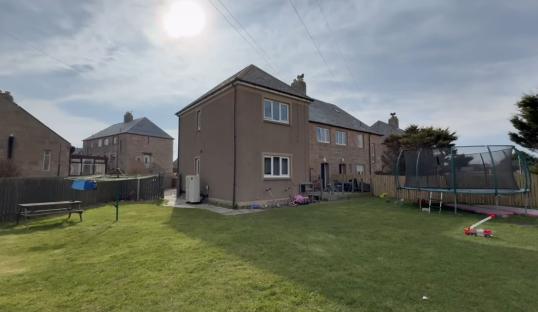 Backyard of a six-bedroom council house with a trampoline and other children's toys.