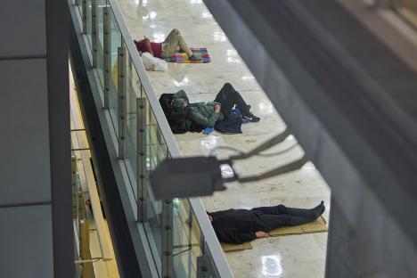 Three people sleeping on the floor of an airport terminal.