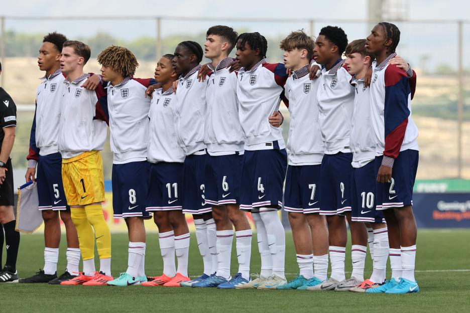 England U-17 players stand with arms around each other during the national anthem.