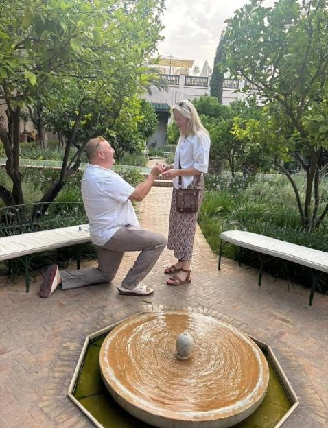 Man proposing to woman in a garden.
