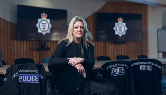 Amber, from the Channel 4 program To Catch a Copper, sits in a chair in a police conference room.