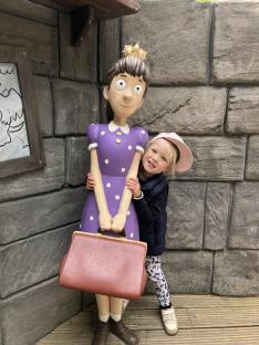 Young girl hugging a large statue of a girl at Warwick Castle.