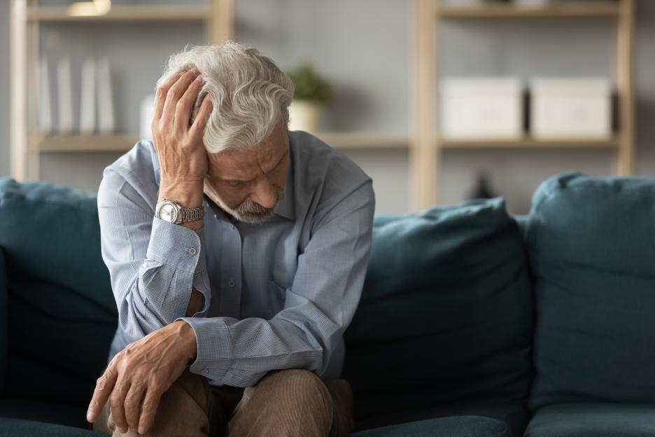 Frustrated middle-aged man sitting on a sofa.