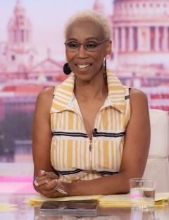 a woman in a yellow and black striped shirt sits at a desk