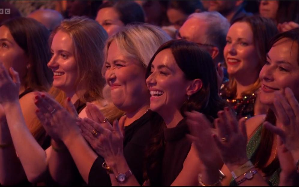 Audience members, mostly women, laughing and applauding.