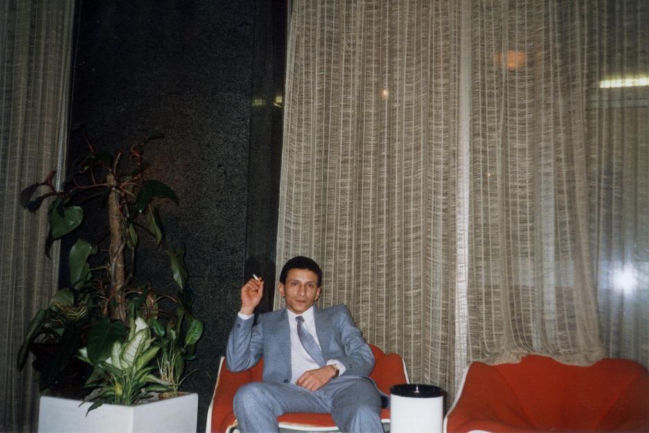 Photo of a man in a suit smoking a cigarette.