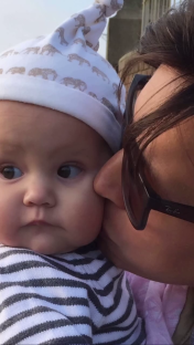 A woman kissing a baby on the cheek.