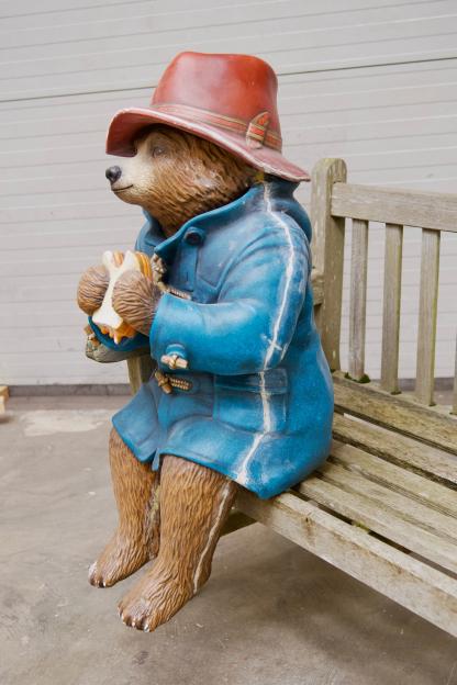 Repaired Paddington Bear statue sitting on a bench, holding a sandwich.