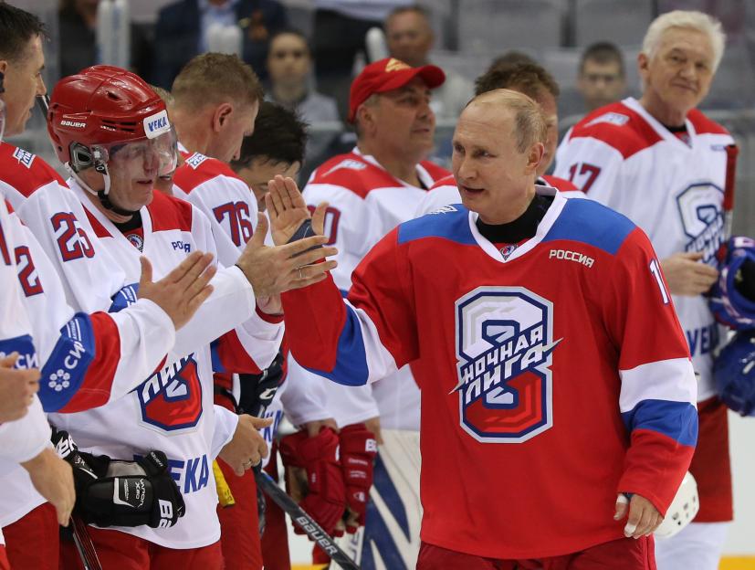 Vladimir Putin high-fiving a hockey player.