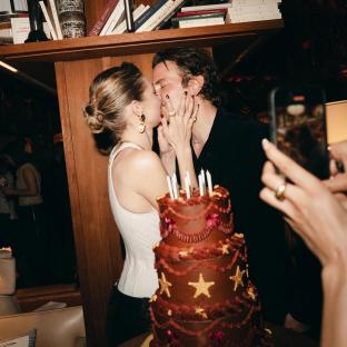 Gigi Hadid and Bradley Cooper kissing in front of a birthday cake.