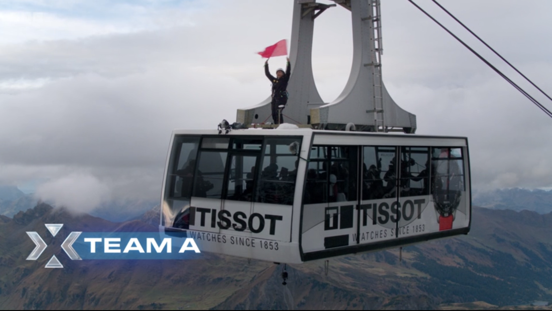 Team A's cable car over mountains; Tissot advertisement visible.