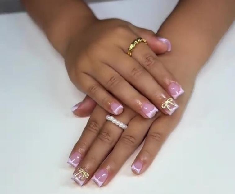 Child's hands with light purple and white nail polish and gold bow accents.