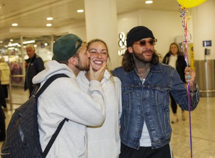 A man kissing a woman on the cheek, while another man holds a balloon.