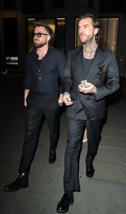 Two men in black suits walking at night.
