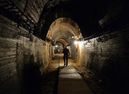 A man walks down a dimly lit tunnel.