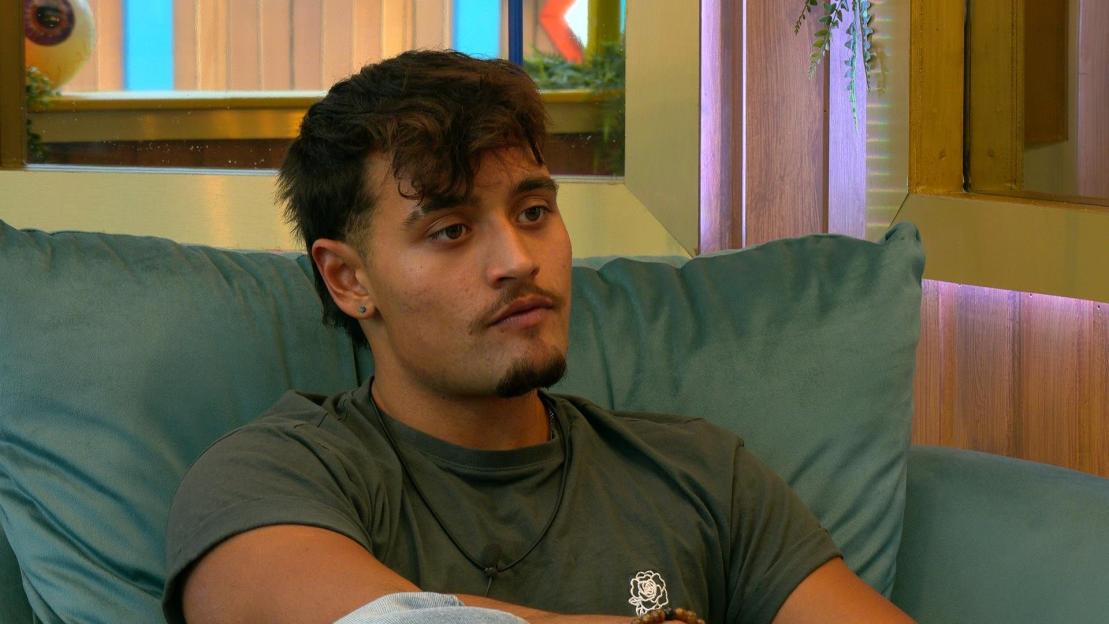 Big Brother contestant Zelah sitting on a teal couch.